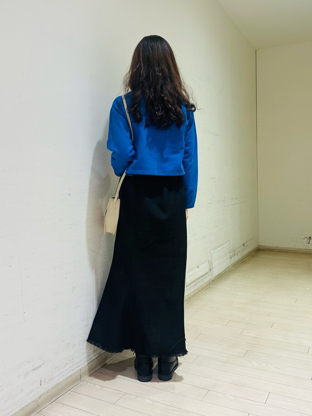 ブルー系のカーディガン/ボレロ、ベージュ系のハンドバッグ、ブラック系のスカートを着用したレディースの冬コーディネートの2枚目の写真