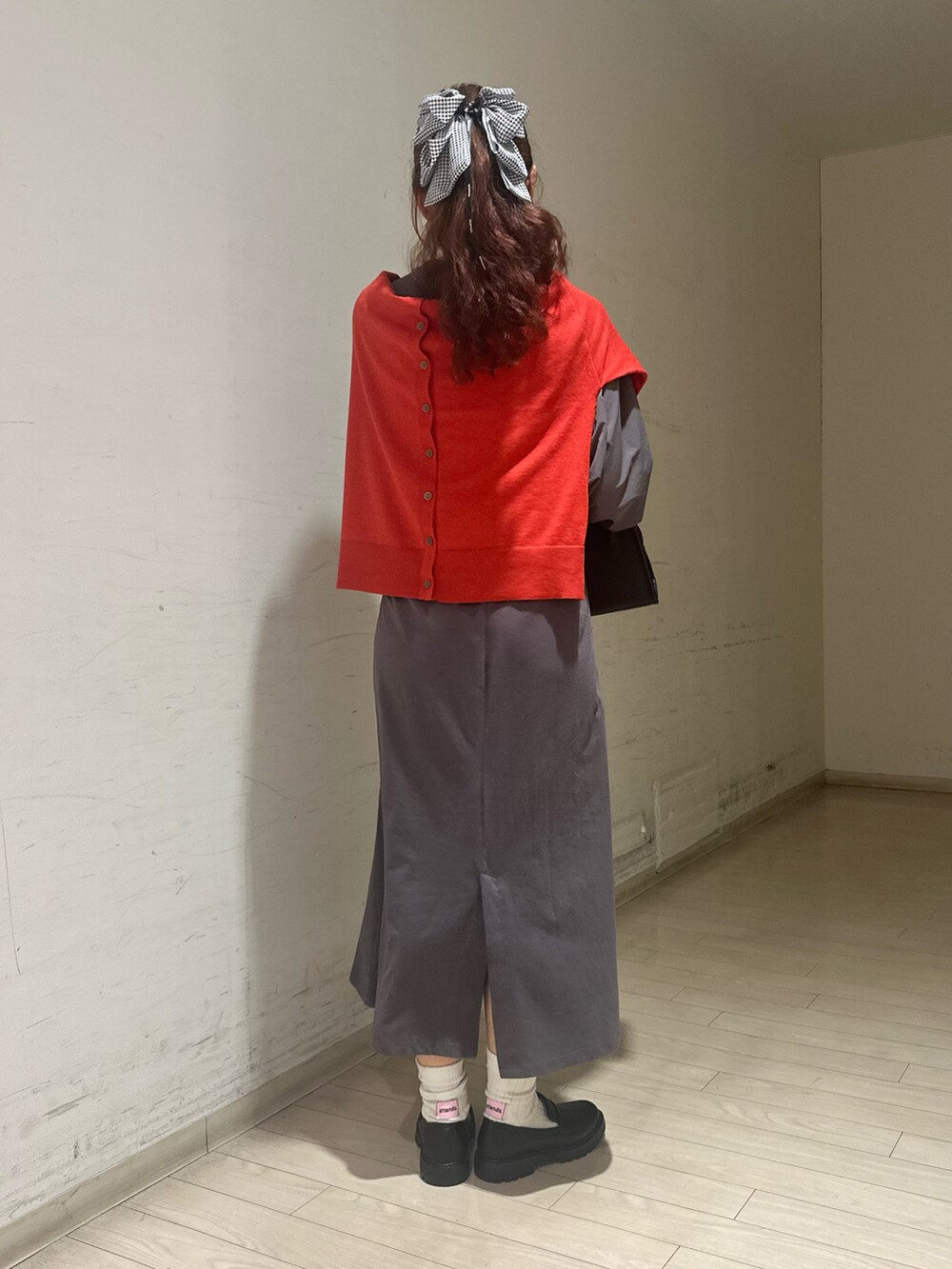 レッド系のカーディガン/ボレロ、グレー系のワンピース、ブラック系のハンドバッグを着用したレディースの秋コーディネートの2枚目の写真