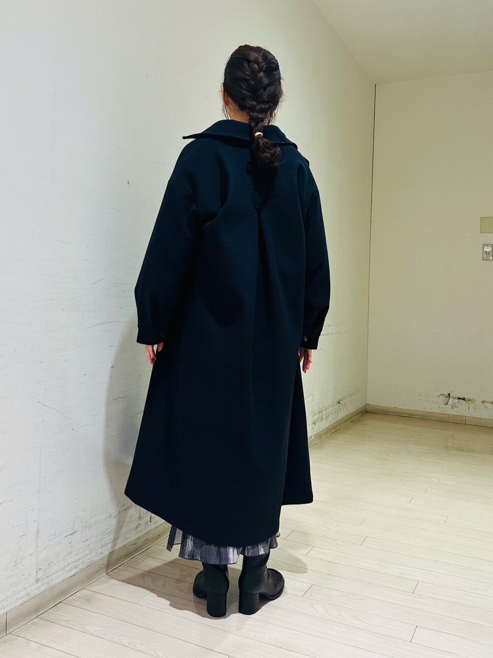 ブルー系のステンカラーコート、ホワイト系のニット/セーター、ブラック系のドレスシューズを着用したレディースの冬コーディネートの2枚目の写真