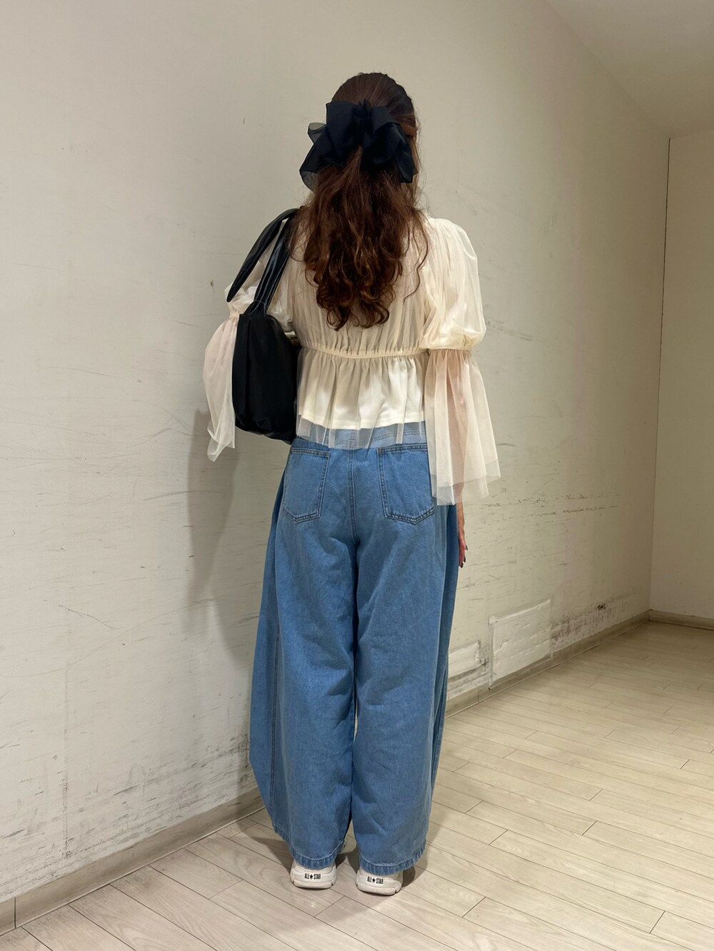 ブラック系のハンドバッグ、ブラウン系のスニーカー、ホワイト系のシャツ/ブラウスを着用したレディースの春コーディネートの2枚目の写真