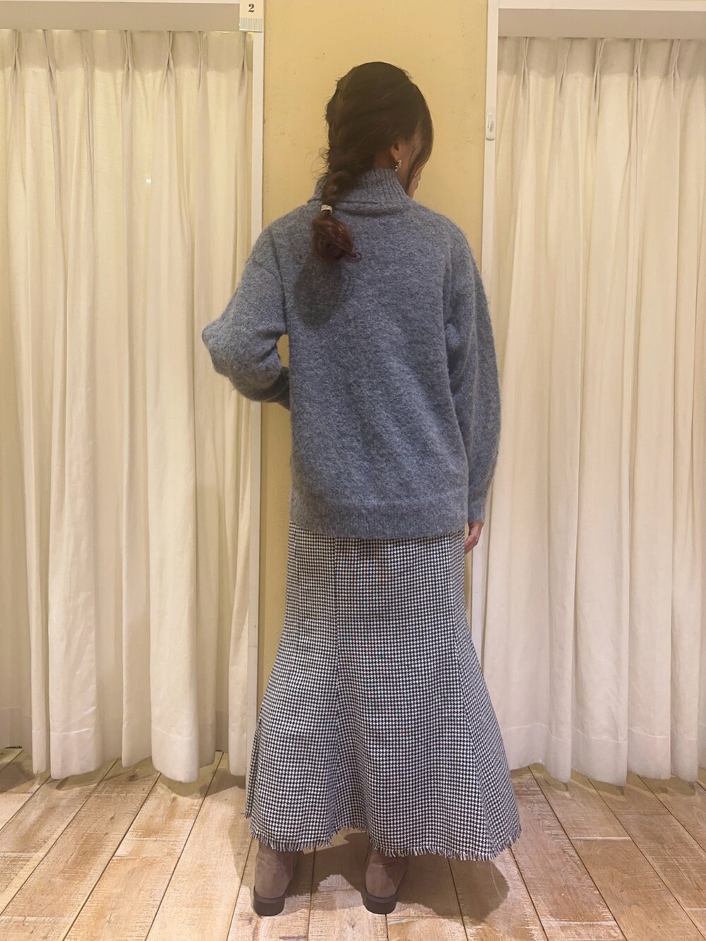 グレー系のニット/セーター、ベージュ系のブーツ、ホワイト系のスカートを着用したレディースの冬コーディネートの2枚目の写真