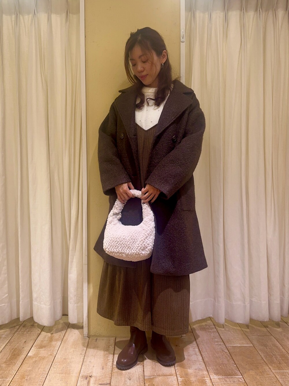 ホワイト系のニット/セーター、ブラウン系のワンピース、ホワイト系のハンドバッグを着用したレディースの秋コーディネートの2枚目の写真