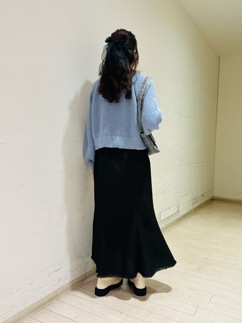 ブルー系のカーディガン/ボレロ、ホワイト系のニット/セーター、ブラック系のスカートを着用したレディースの冬コーディネートの3枚目の写真