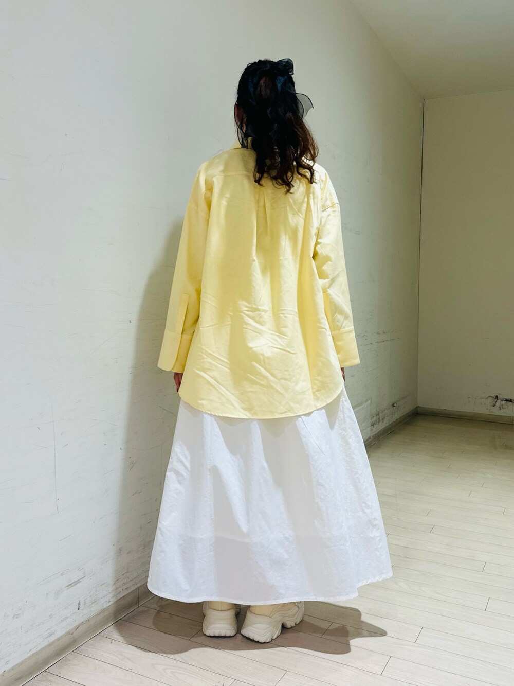 イエロー系のシャツ/ブラウス、ホワイト系のTシャツ/カットソー、ブラック系のハンドバッグを着用したレディースの冬コーディネートの4枚目の写真