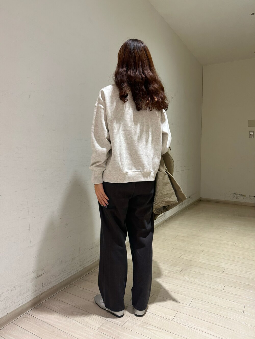 グリーン系のステンカラーコート、グレー系のTシャツ/カットソー、グレー系のハンドバッグを着用したレディースの秋コーディネートの4枚目の写真
