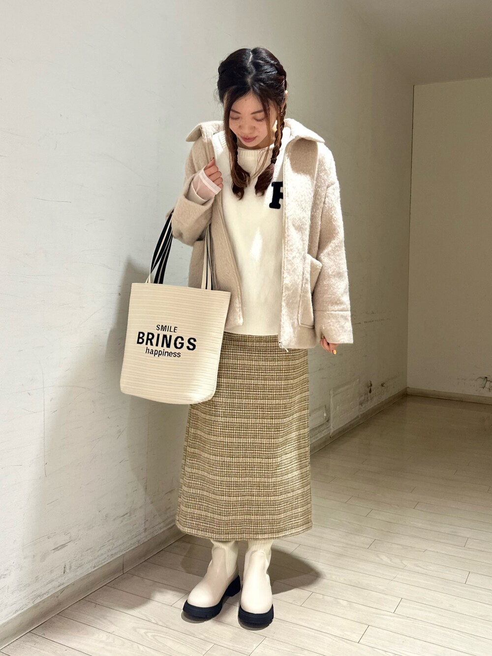 ベージュ系のノーカラージャケット、ホワイト系のニット/セーター、イエロー系のスカートを着用したレディースの冬コーディネートの2枚目の写真