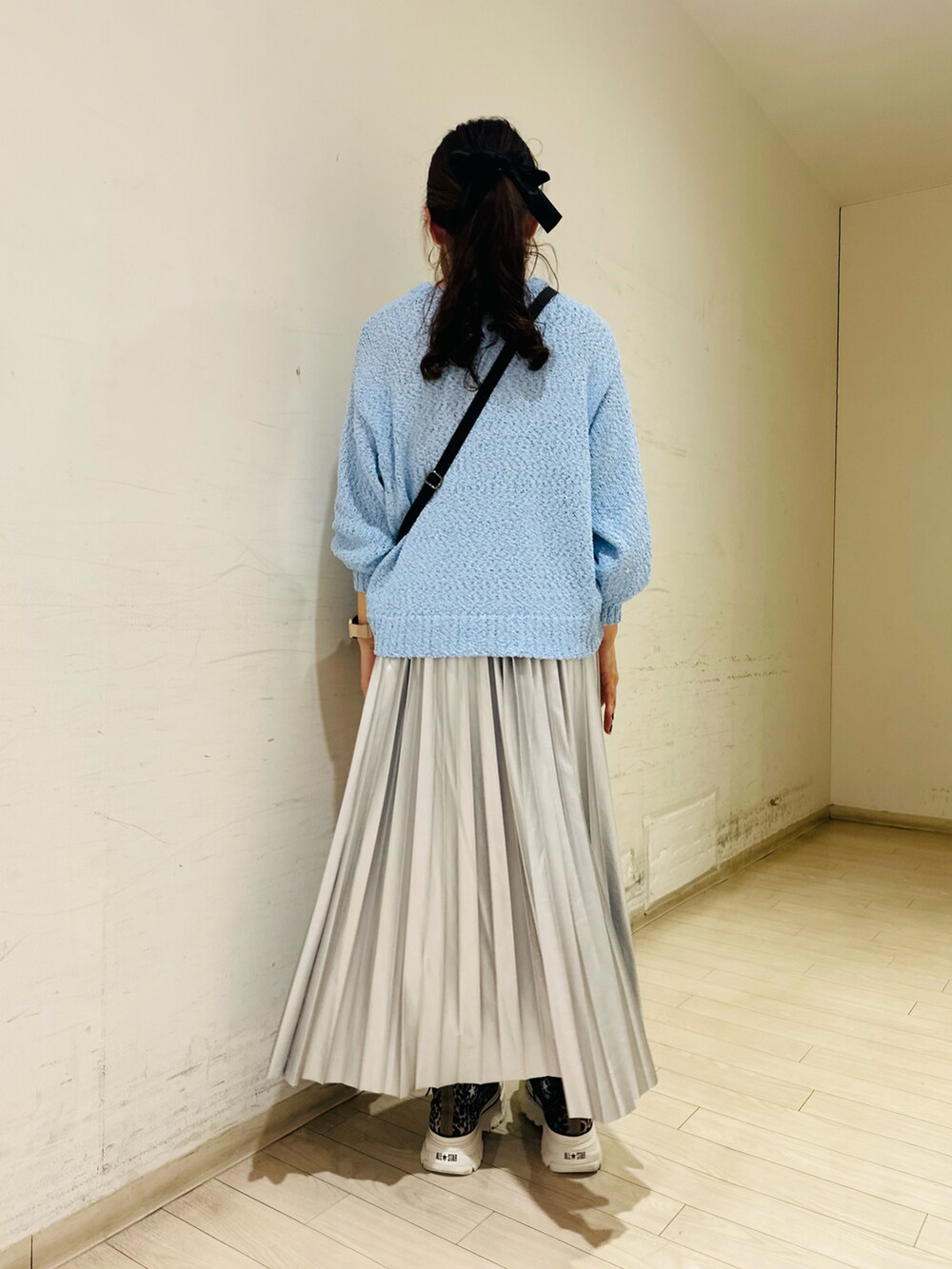 ブルー系のニット/セーター、ブラック系のハンドバッグ、シルバー系のスカートを着用したレディースの冬コーディネートの2枚目の写真