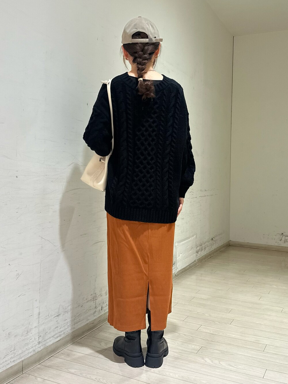 ホワイト系のハンドバッグ、ブラック系のブーツ、ブラック系のニット/セーターを着用したレディースの冬コーディネートの3枚目の写真