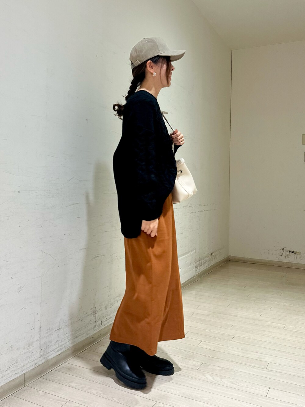 ホワイト系のハンドバッグ、ブラック系のブーツ、ブラック系のニット/セーターを着用したレディースの冬コーディネートの2枚目の写真