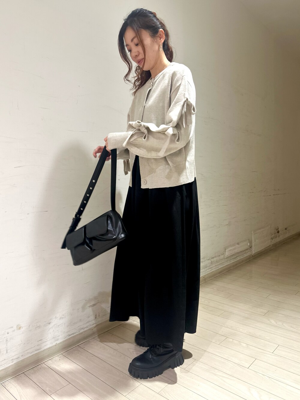 ホワイト系のトップス、グレー系のワンピース、ブラック系のハンドバッグを着用したレディースの冬コーディネートの2枚目の写真