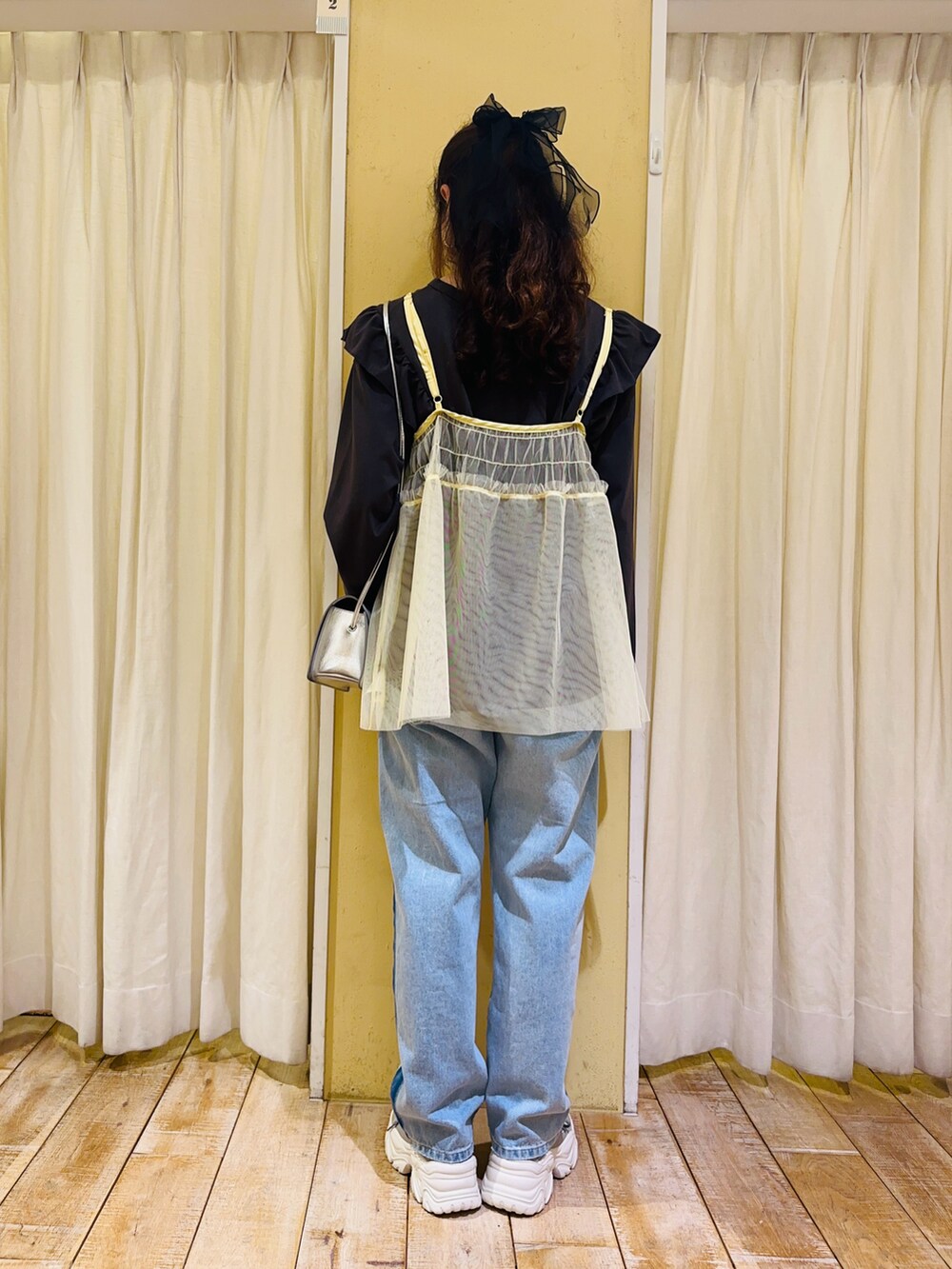 グレー系のTシャツ/カットソー、イエロー系のトップス、シルバー系のハンドバッグを着用したレディースの冬コーディネートの3枚目の写真