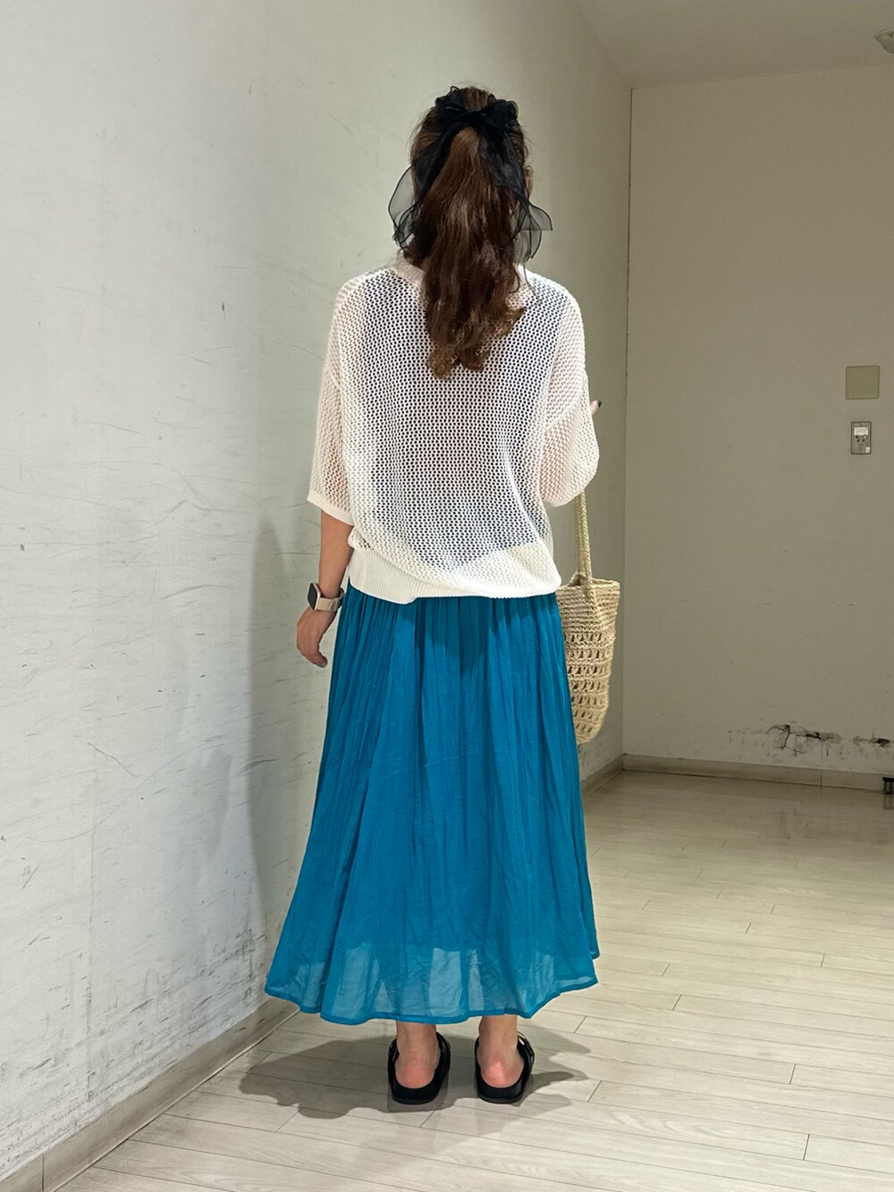 ホワイト系のニット/セーター、ブルー系のスカート、ベージュ系のハンドバッグを着用したレディースの夏コーディネートの2枚目の写真
