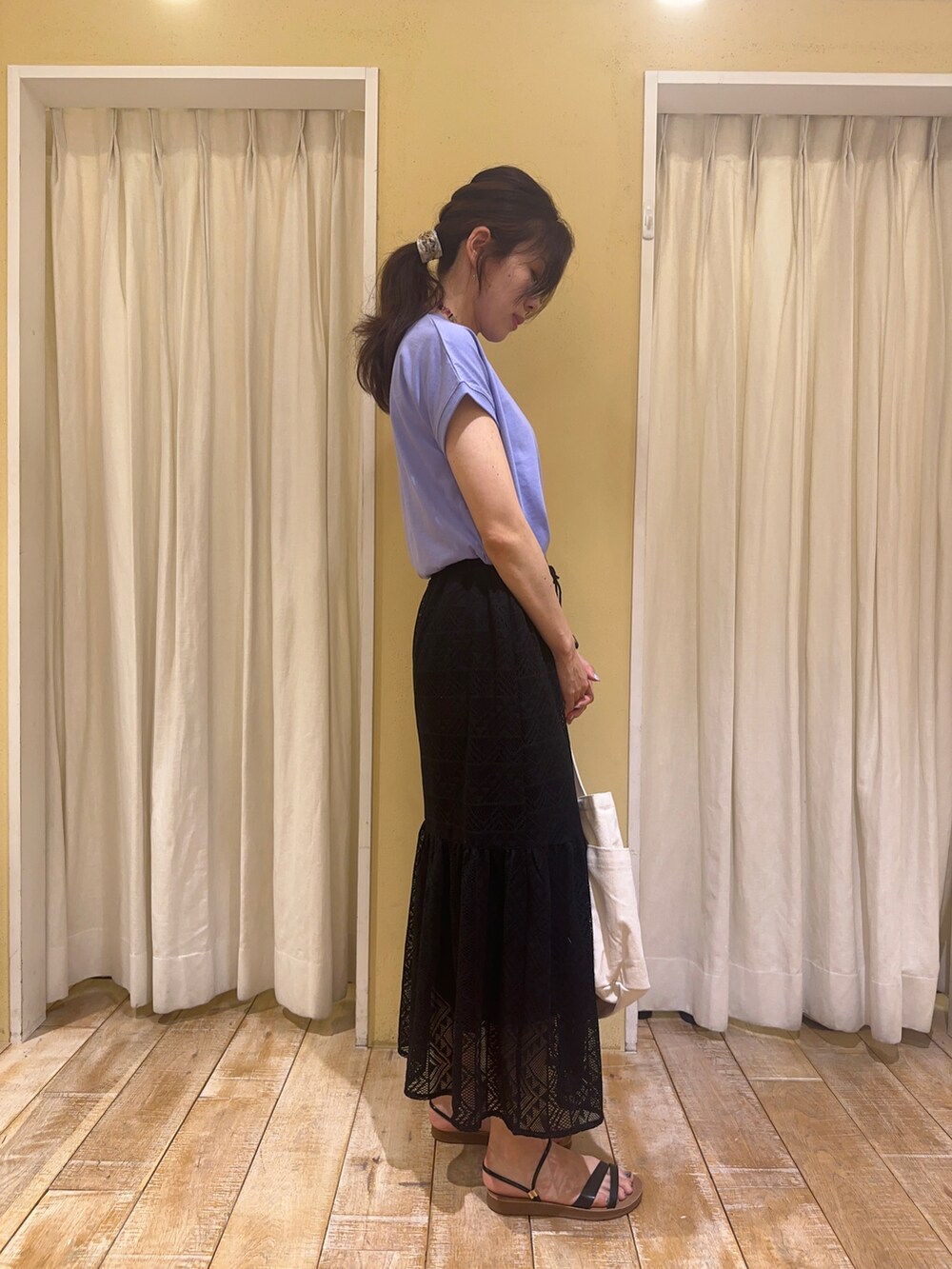 ブラック系のスカート、ホワイト系のハンドバッグ、ブラック系のサンダルを着用したレディースの春コーディネートの2枚目の写真