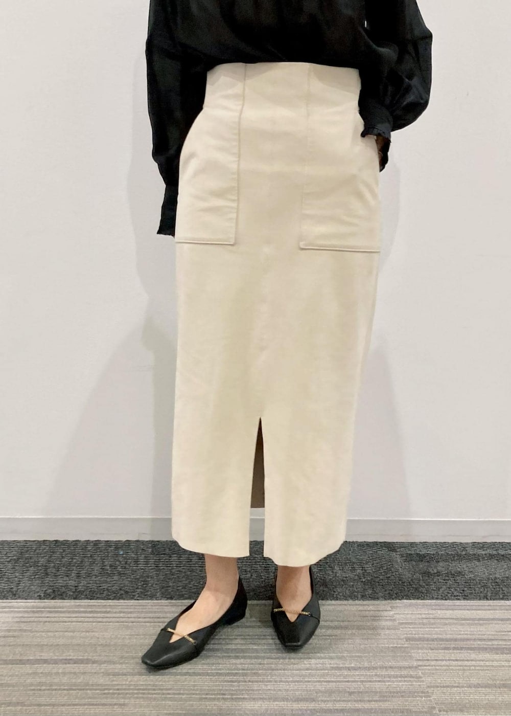 ブラック系のトートバッグ、ブラック系のパンプス、ホワイト系のスカートを着用したレディースの秋コーディネートの5枚目の写真