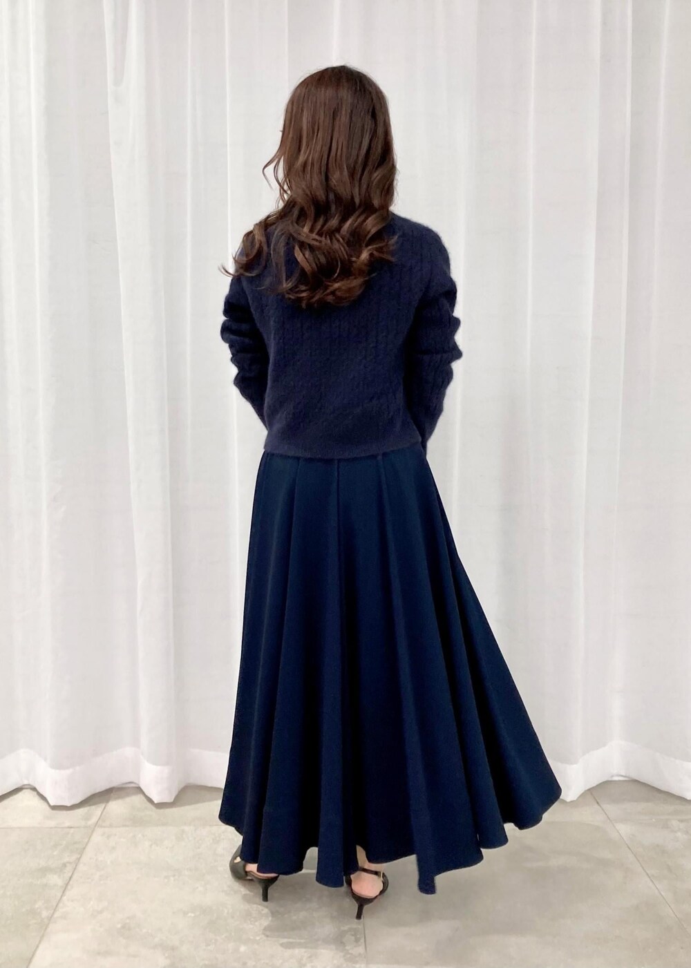 ブラック系のパンプス、ブラック系のトートバッグ、ブルー系のニット/セーターを着用したレディースの秋コーディネートの3枚目の写真