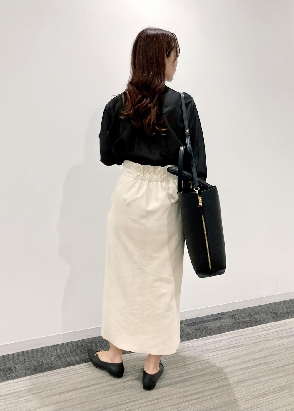 ブラック系のトートバッグ、ブラック系のパンプス、ホワイト系のスカートを着用したレディースの秋コーディネートの3枚目の写真