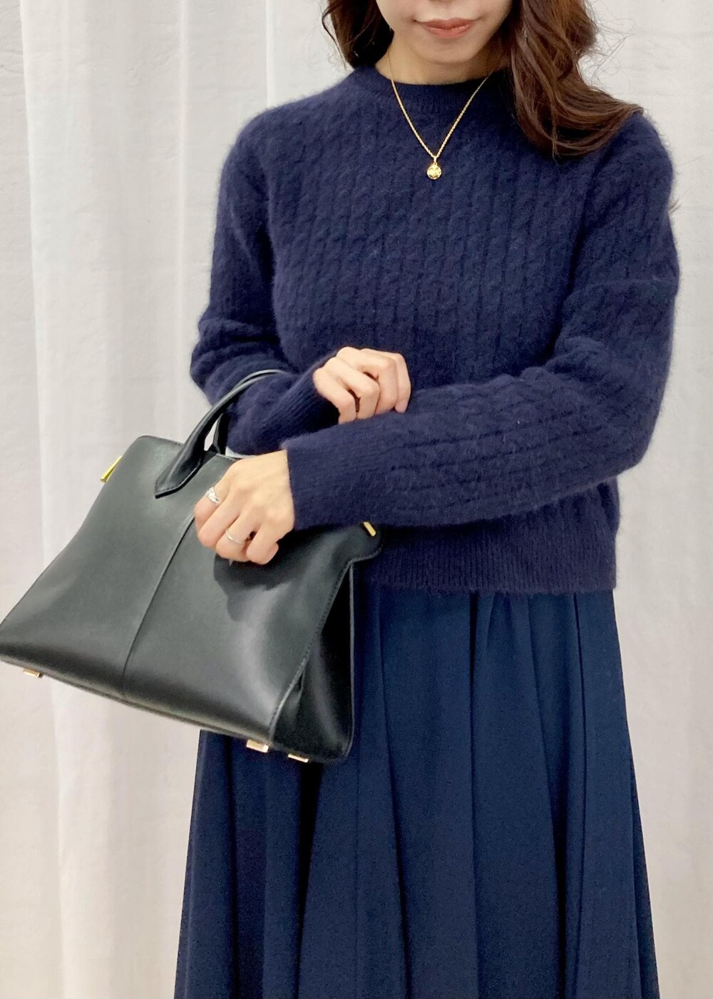 ブラック系のパンプス、ブラック系のトートバッグ、ブルー系のニット/セーターを着用したレディースの秋コーディネートの5枚目の写真