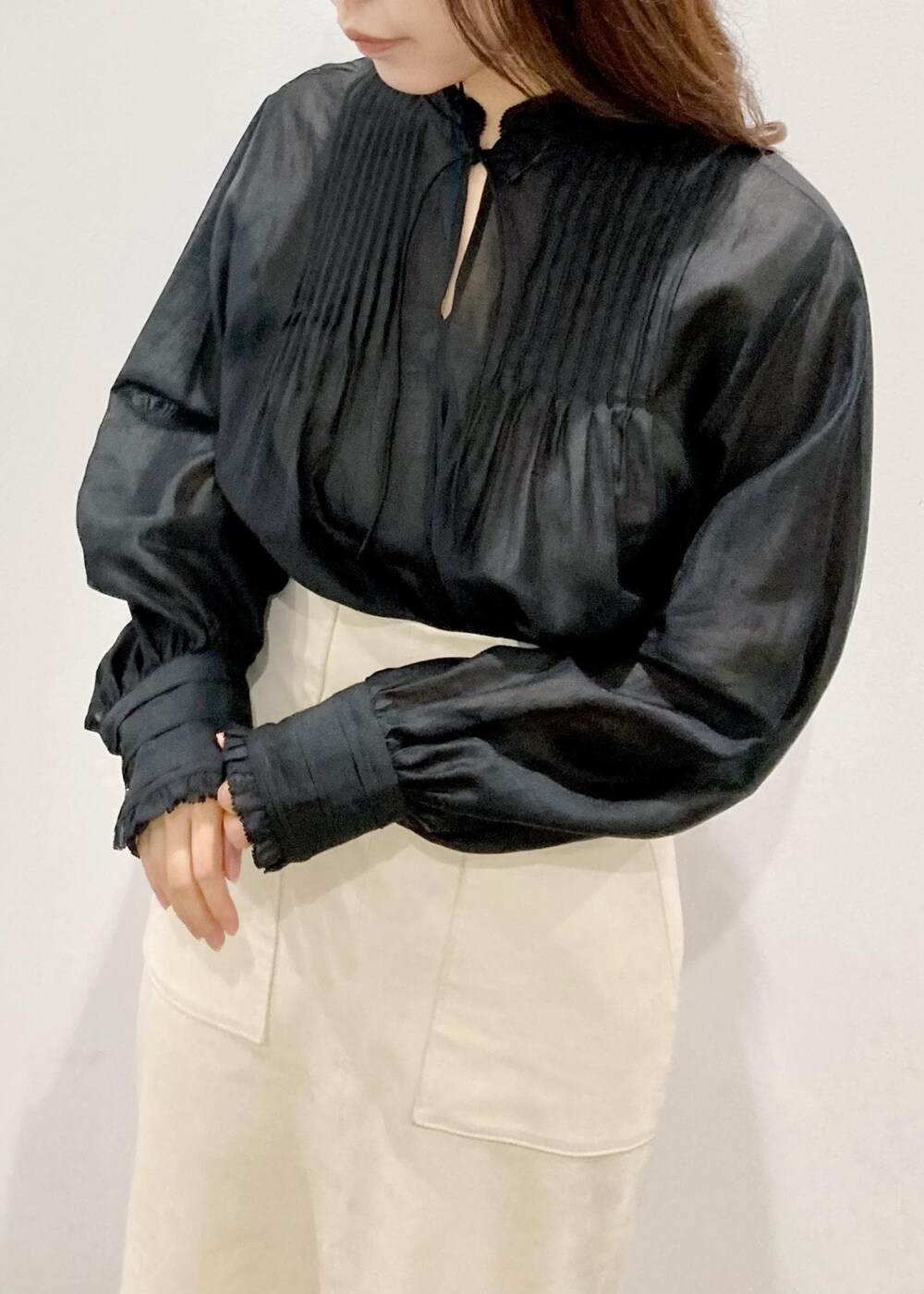 ブラック系のトートバッグ、ブラック系のパンプス、ホワイト系のスカートを着用したレディースの秋コーディネートの4枚目の写真