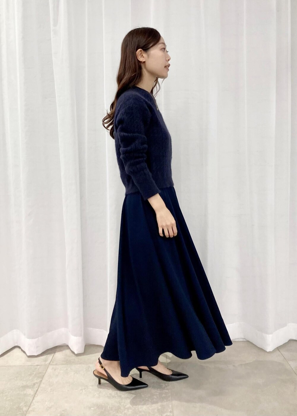 ブラック系のパンプス、ブラック系のトートバッグ、ブルー系のニット/セーターを着用したレディースの秋コーディネートの2枚目の写真