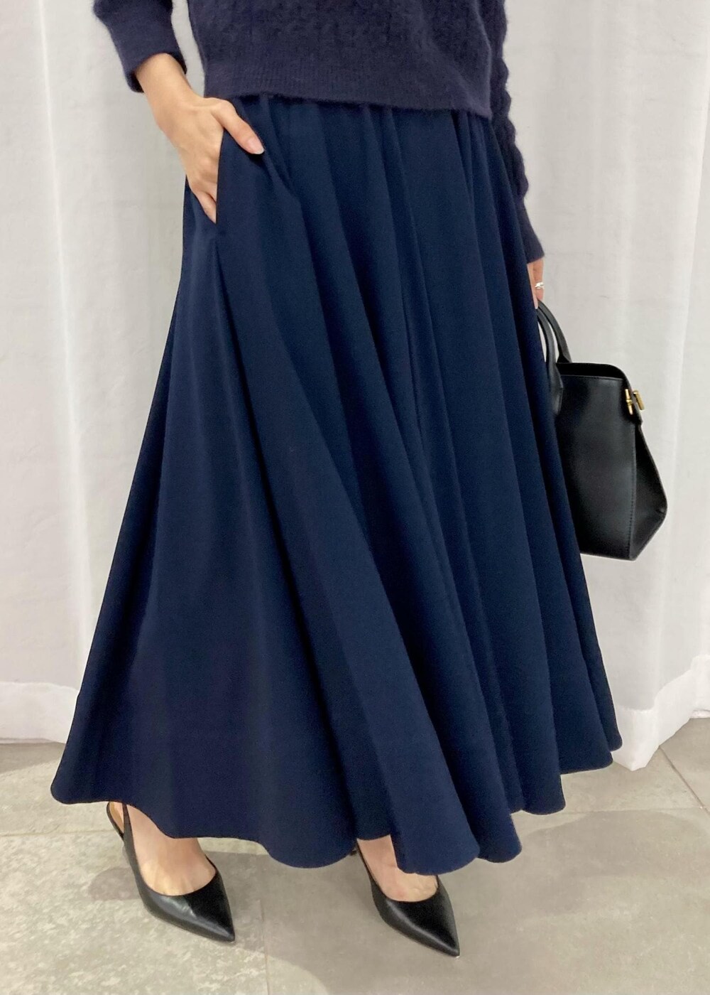 ブラック系のパンプス、ブラック系のトートバッグ、ブルー系のニット/セーターを着用したレディースの秋コーディネートの6枚目の写真