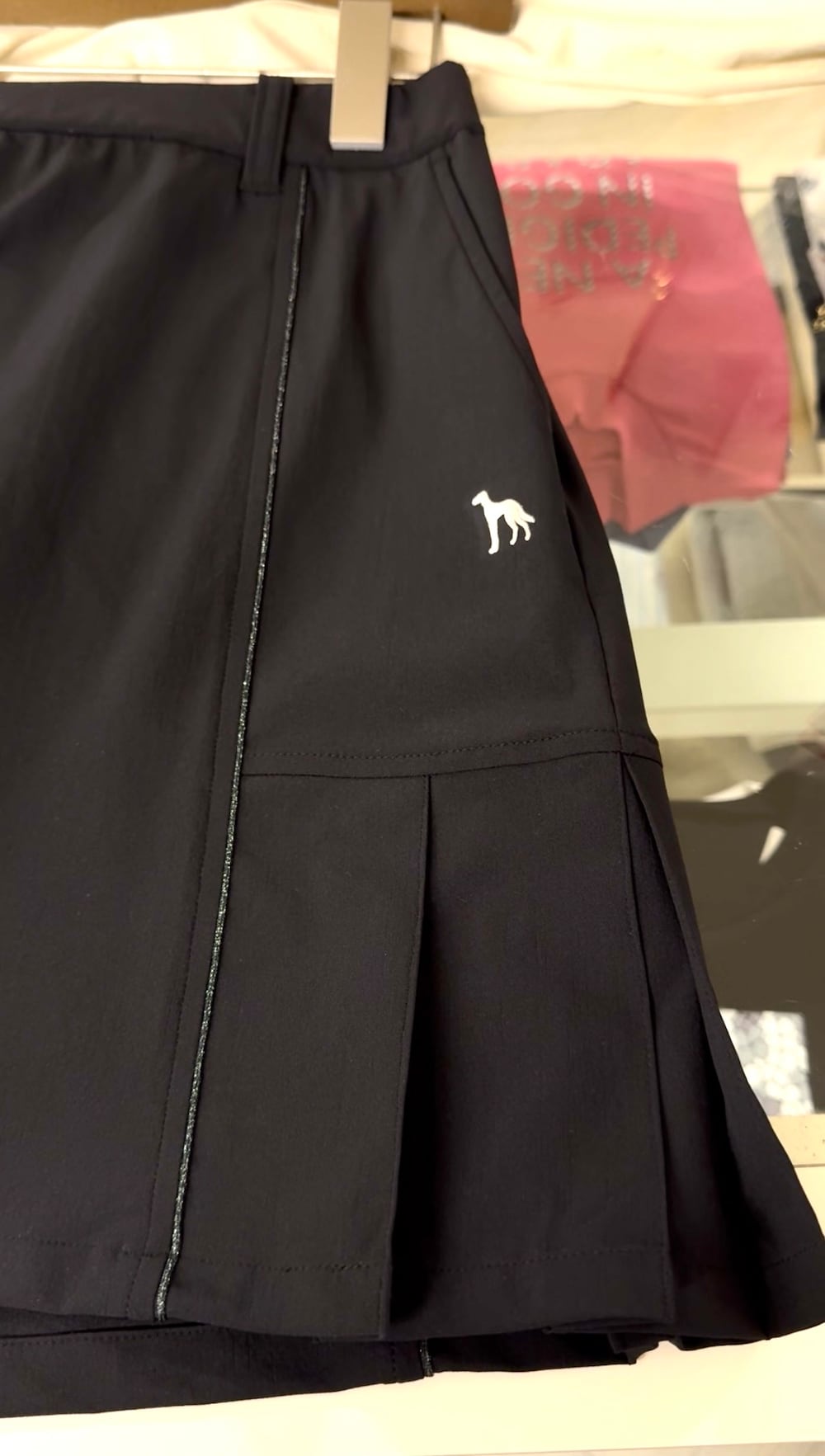 ブラック系のポロシャツ、ブラック系のスカート、ブラック系のトートバッグを着用したレディースの夏コーディネートの5枚目の写真