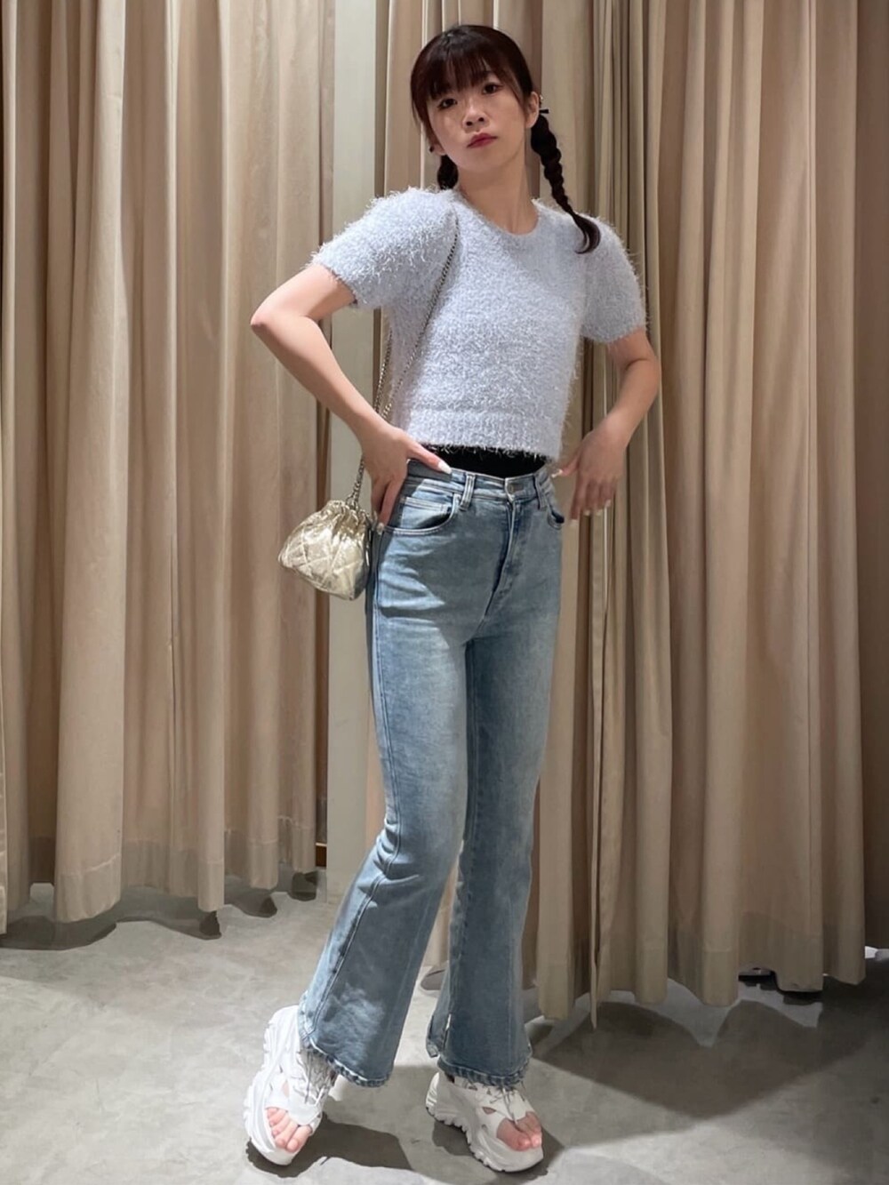 ブルー系のニット/セーター、ゴールド系のショルダーバッグ、ホワイト系のサンダルを着用したレディースの春コーディネートの2枚目の写真