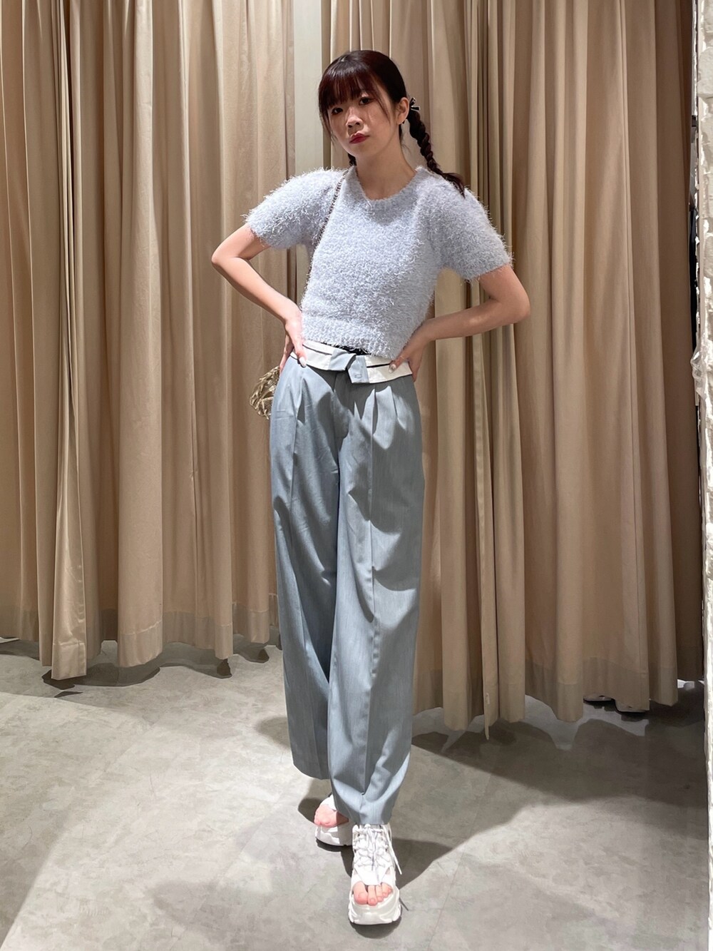 ゴールド系のショルダーバッグ、ホワイト系のサンダル、ブルー系のニット/セーターを着用したレディースの春コーディネートの2枚目の写真