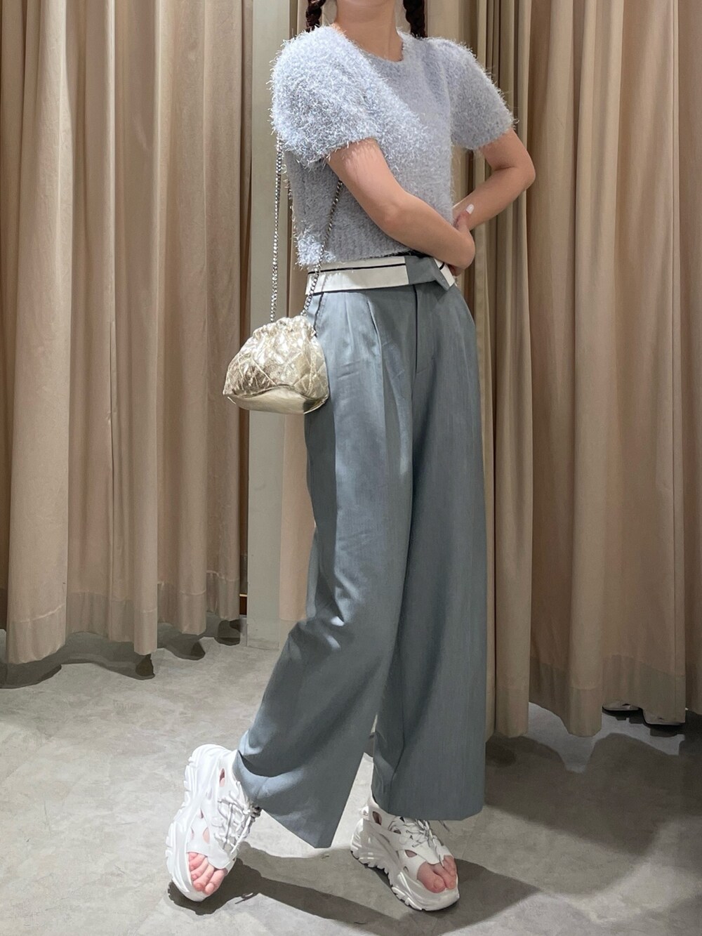 ゴールド系のショルダーバッグ、ホワイト系のサンダル、ブルー系のニット/セーターを着用したレディースの春コーディネートの4枚目の写真