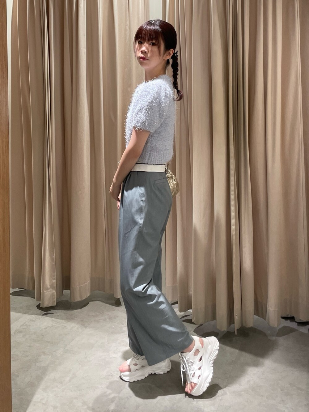 ゴールド系のショルダーバッグ、ホワイト系のサンダル、ブルー系のニット/セーターを着用したレディースの春コーディネートの3枚目の写真