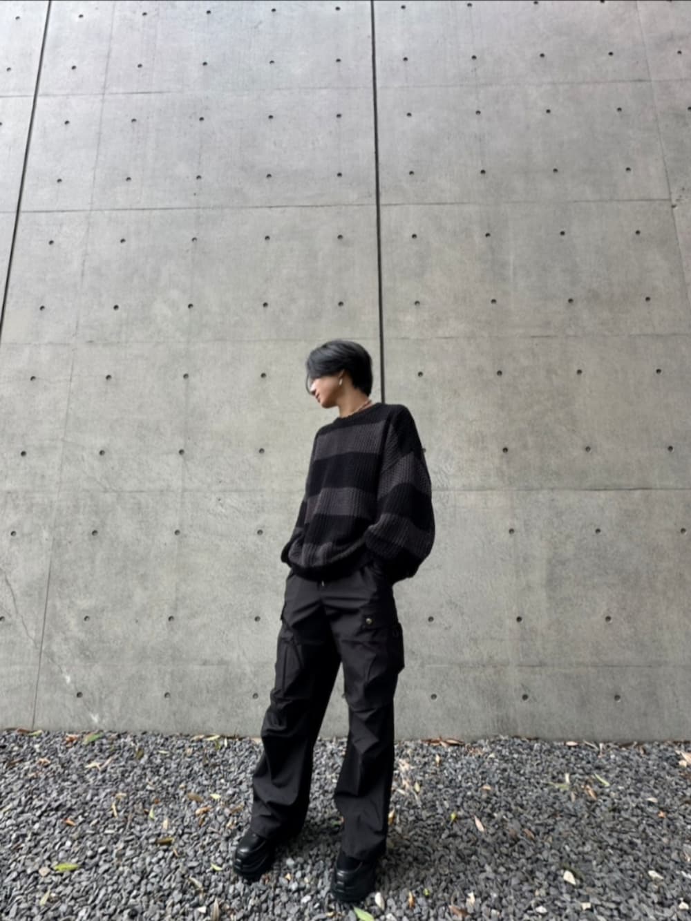 ブラック系のカーゴパンツ、グレー系のニット/セーター、ブラック系のスニーカーを着用したメンズの秋コーディネートの3枚目の写真