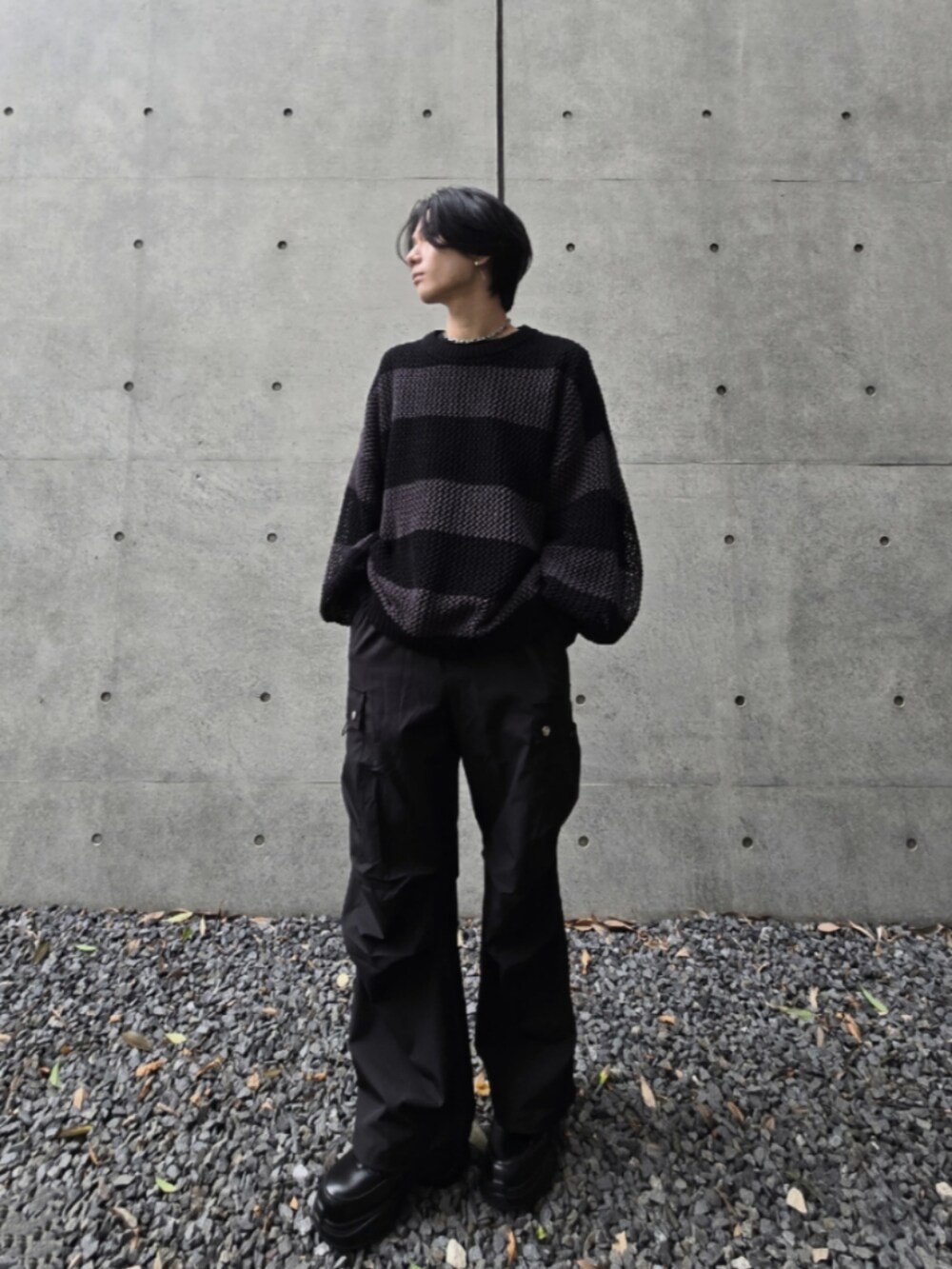 ブラック系のカーゴパンツ、グレー系のニット/セーター、ブラック系のスニーカーを着用したメンズの秋コーディネートの2枚目の写真