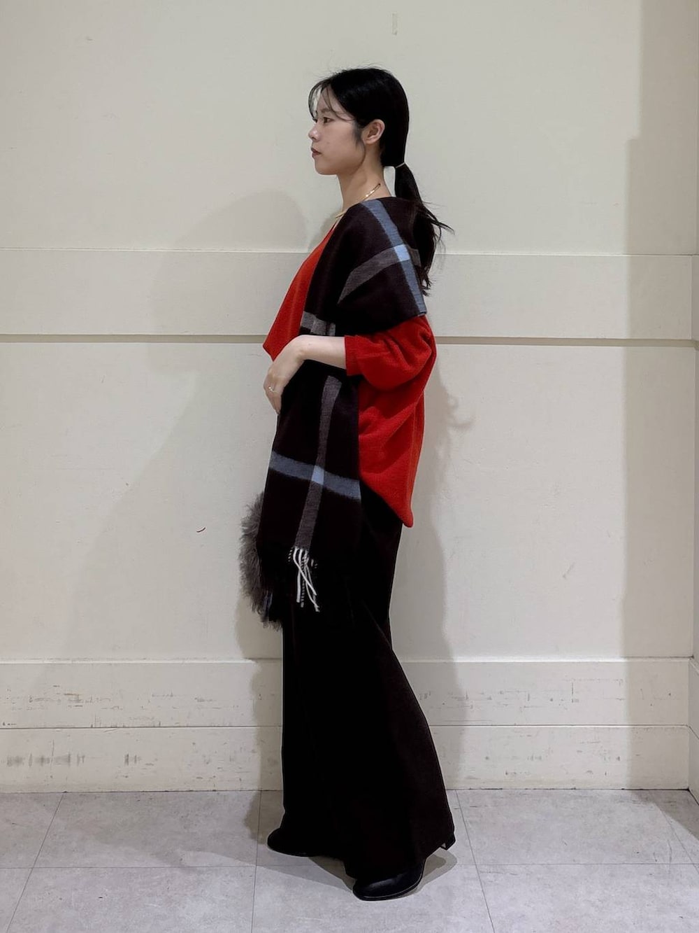 ブラウン系のトートバッグ、ブラック系のブーツ、レッド系のニット/セーターを着用したレディースの秋コーディネートの2枚目の写真