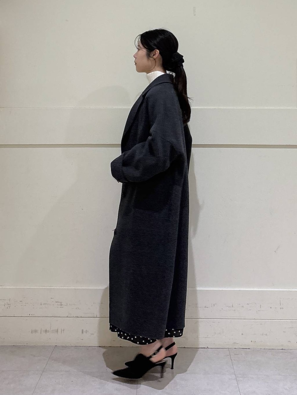 ホワイト系のニット/セーター、グレー系のチェスターコート、ブラウン系のショルダーバッグを着用したレディースの秋コーディネートの2枚目の写真