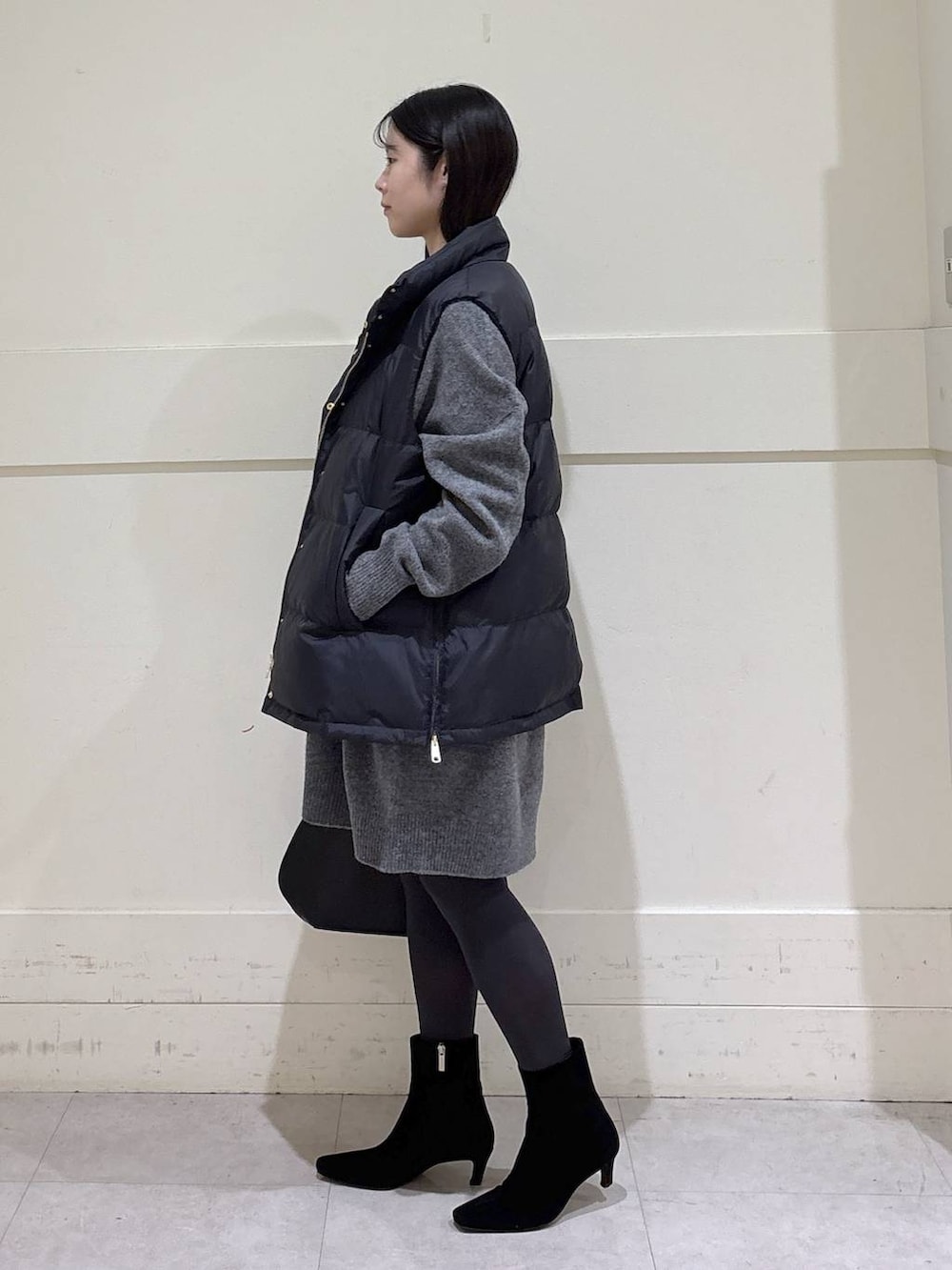 ブラック系のトートバッグ、ブラック系のダウンベスト、グレー系のニット/セーターを着用したレディースの秋コーディネートの2枚目の写真