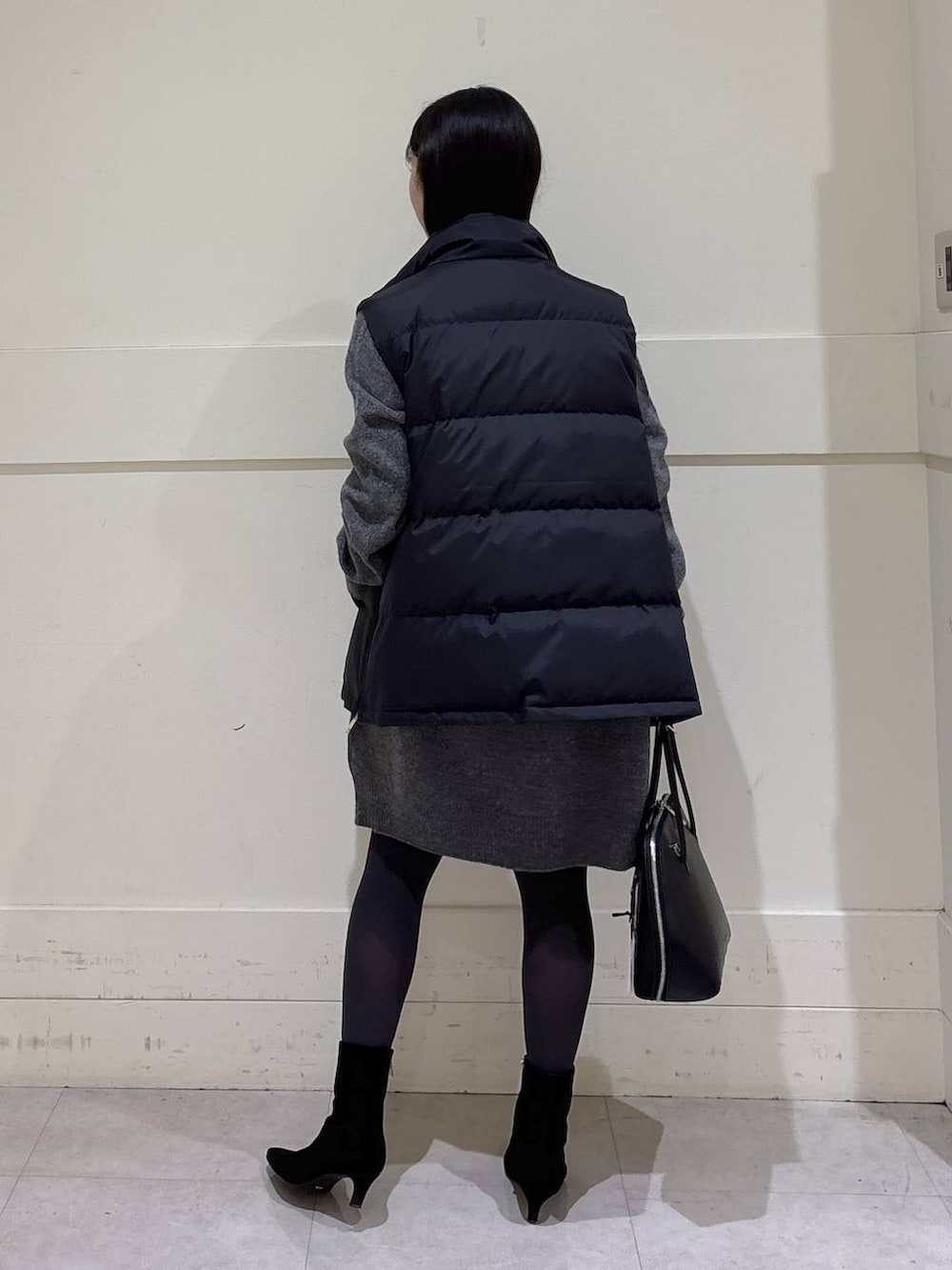 ブラック系のトートバッグ、ブラック系のダウンベスト、グレー系のニット/セーターを着用したレディースの秋コーディネートの3枚目の写真