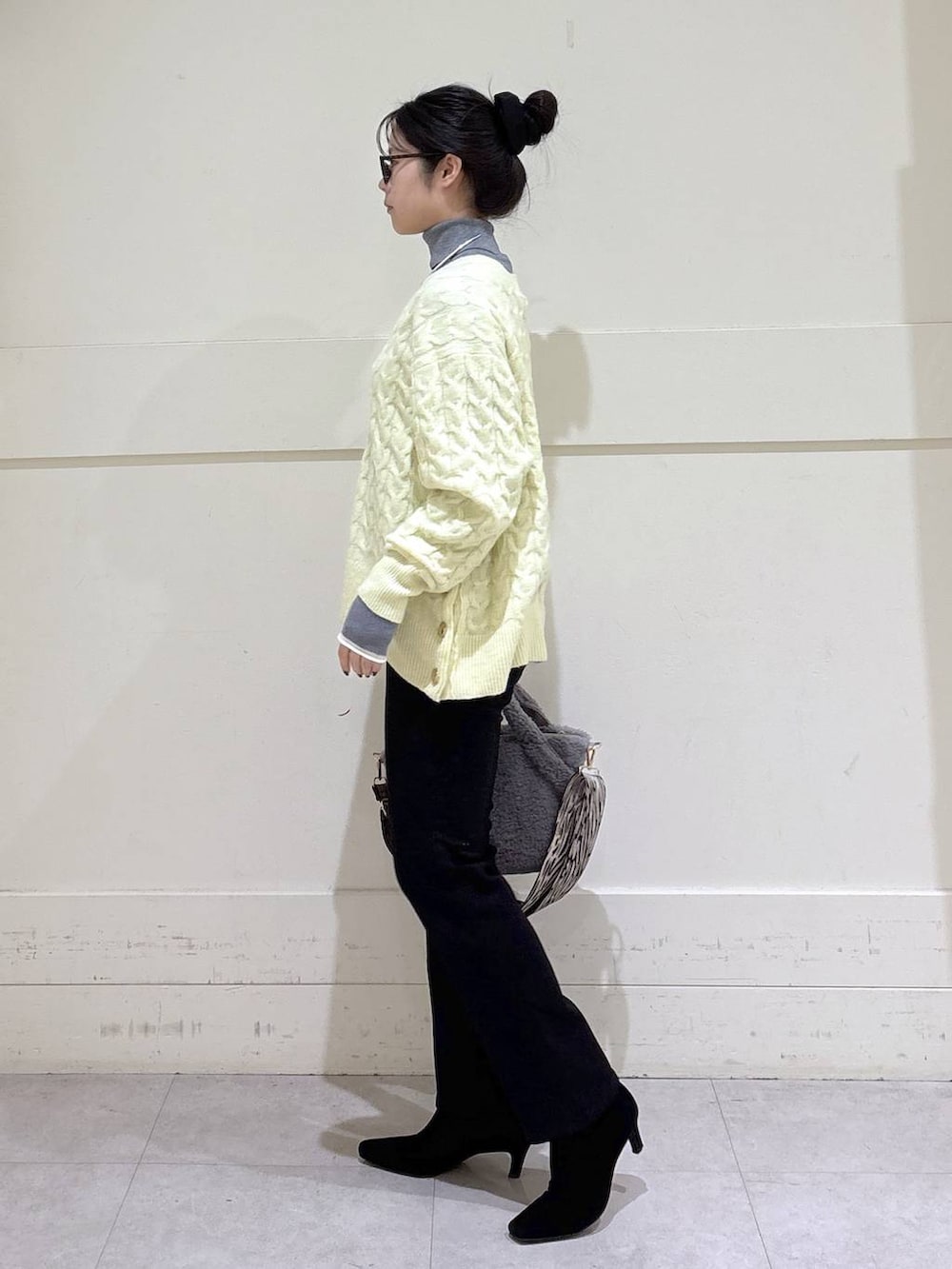 ブラック系のデニムパンツ、グレー系のトートバッグ、グレー系のニット/セーターを着用したレディースの秋コーディネートの2枚目の写真