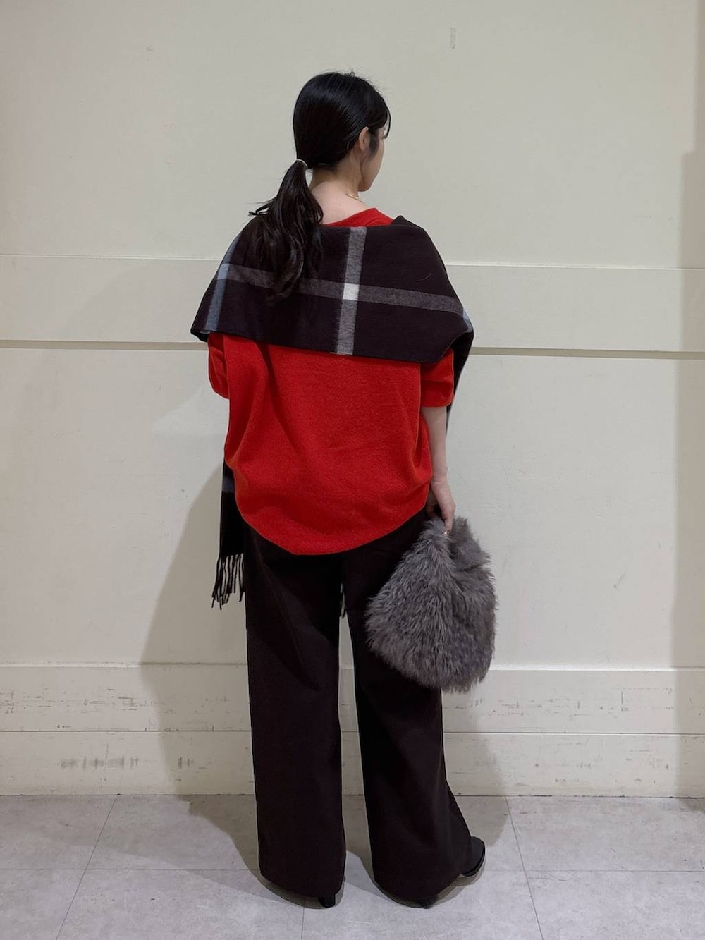 ブラウン系のトートバッグ、ブラック系のブーツ、レッド系のニット/セーターを着用したレディースの秋コーディネートの3枚目の写真