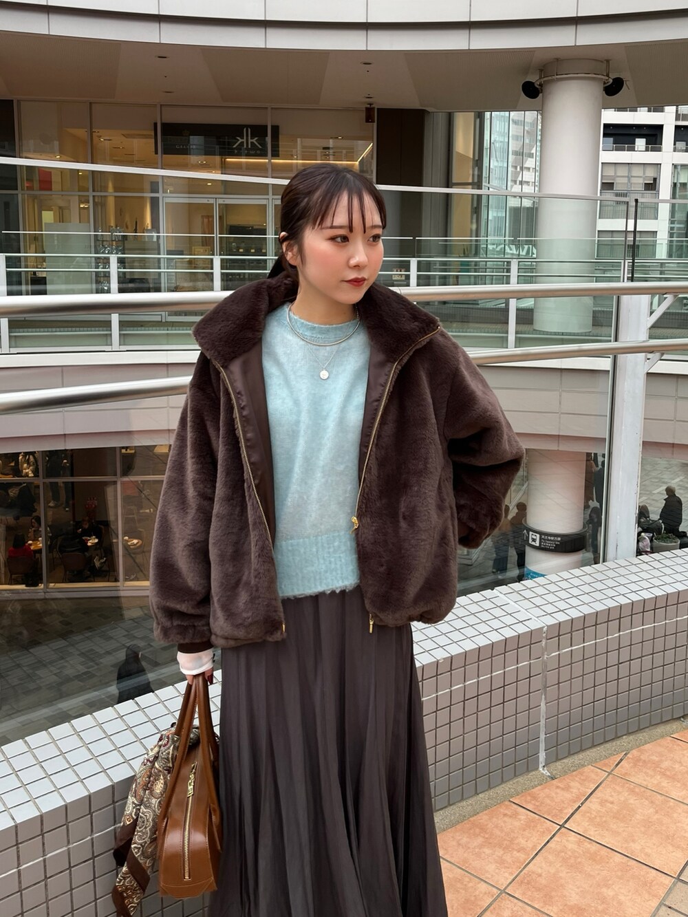 グレー系のスカート、ブラウン系のショルダーバッグ、ブラウン系のその他アウターを着用したレディースの冬コーディネートの2枚目の写真