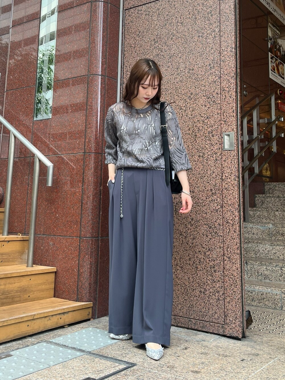 グレー系のスラックス、シルバー系のパンプス、ブラック系のショルダーバッグを着用したレディースの秋コーディネートの2枚目の写真