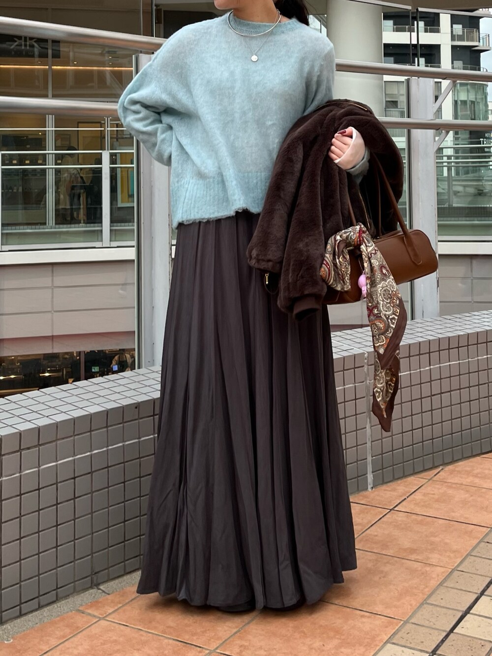 グレー系のスカート、ブラウン系のショルダーバッグ、ブラウン系のその他アウターを着用したレディースの冬コーディネートの4枚目の写真