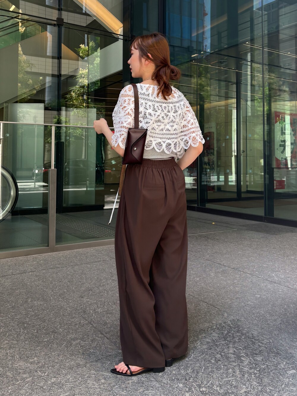 ブラウン系のスラックス、ブラック系のサンダル、グレー系のTシャツ/カットソーを着用したレディースの夏コーディネートの2枚目の写真