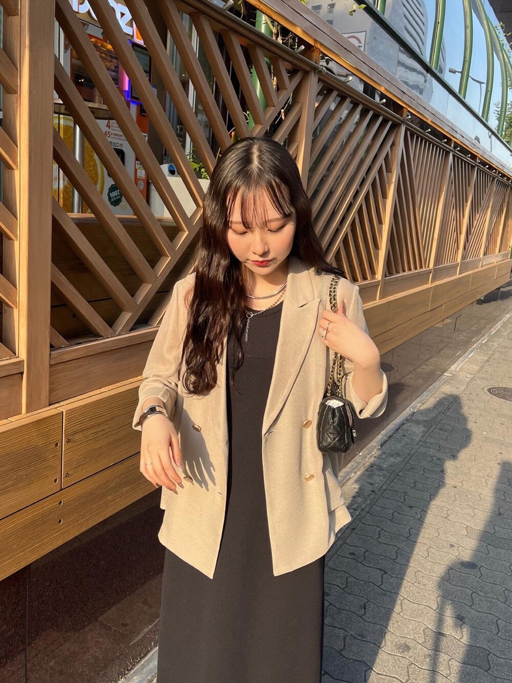 ブラック系のワンピース/ドレス、ベージュ系のテーラードジャケット、ブラック系のショルダーバッグを着用したレディースの夏コーディネートの2枚目の写真