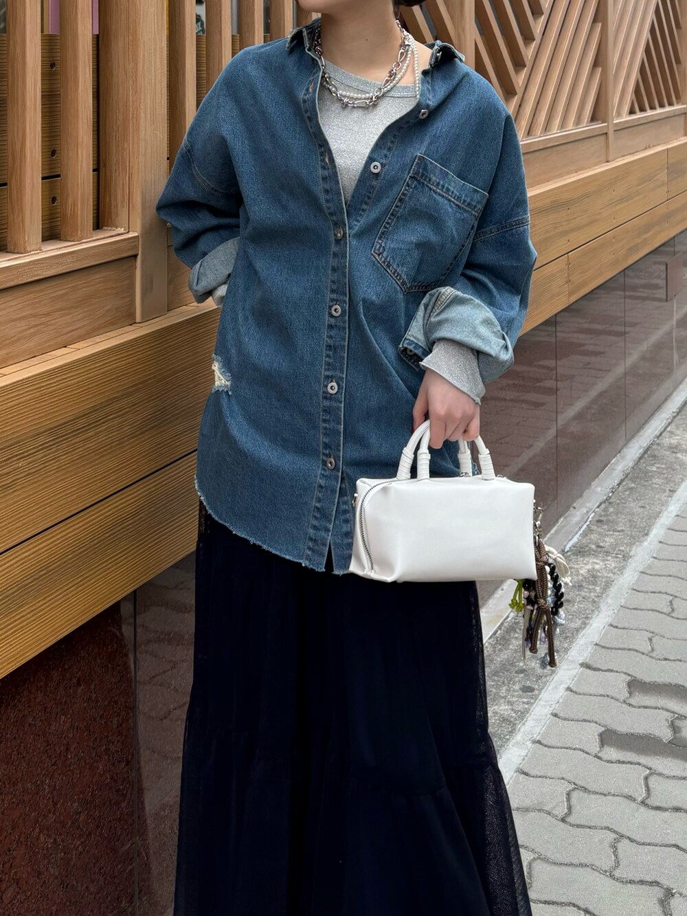 ブルー系のスカート、ブラウン系のブーツ、ホワイト系のショルダーバッグを着用したレディースの冬コーディネートの6枚目の写真