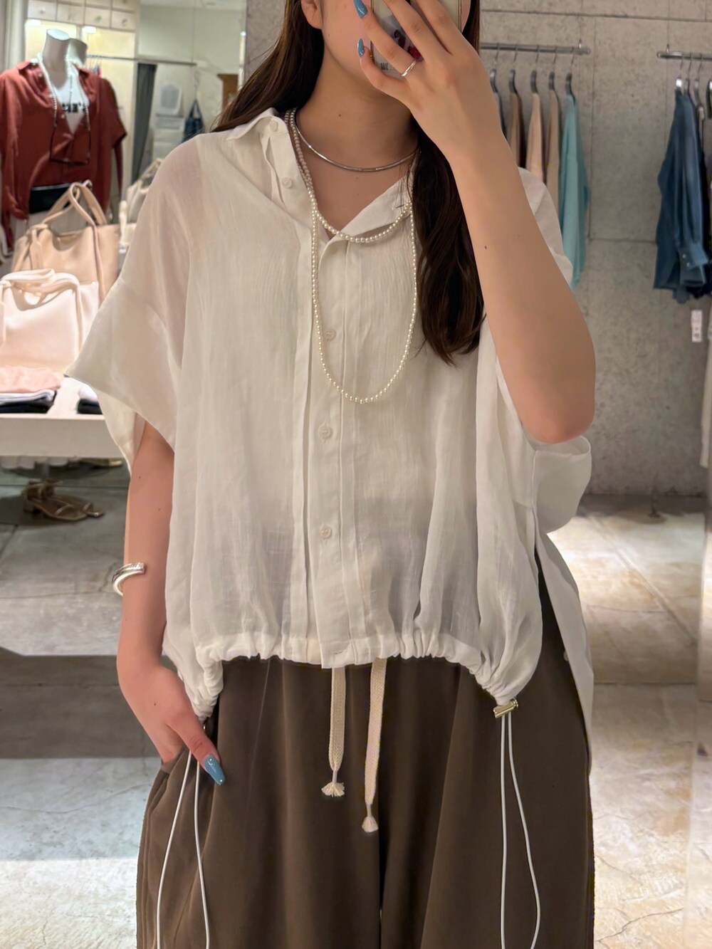 ブラウン系のその他パンツ、ホワイト系のシャツ/ブラウス、シルバー系のサンダルを着用したレディースの夏コーディネートの3枚目の写真