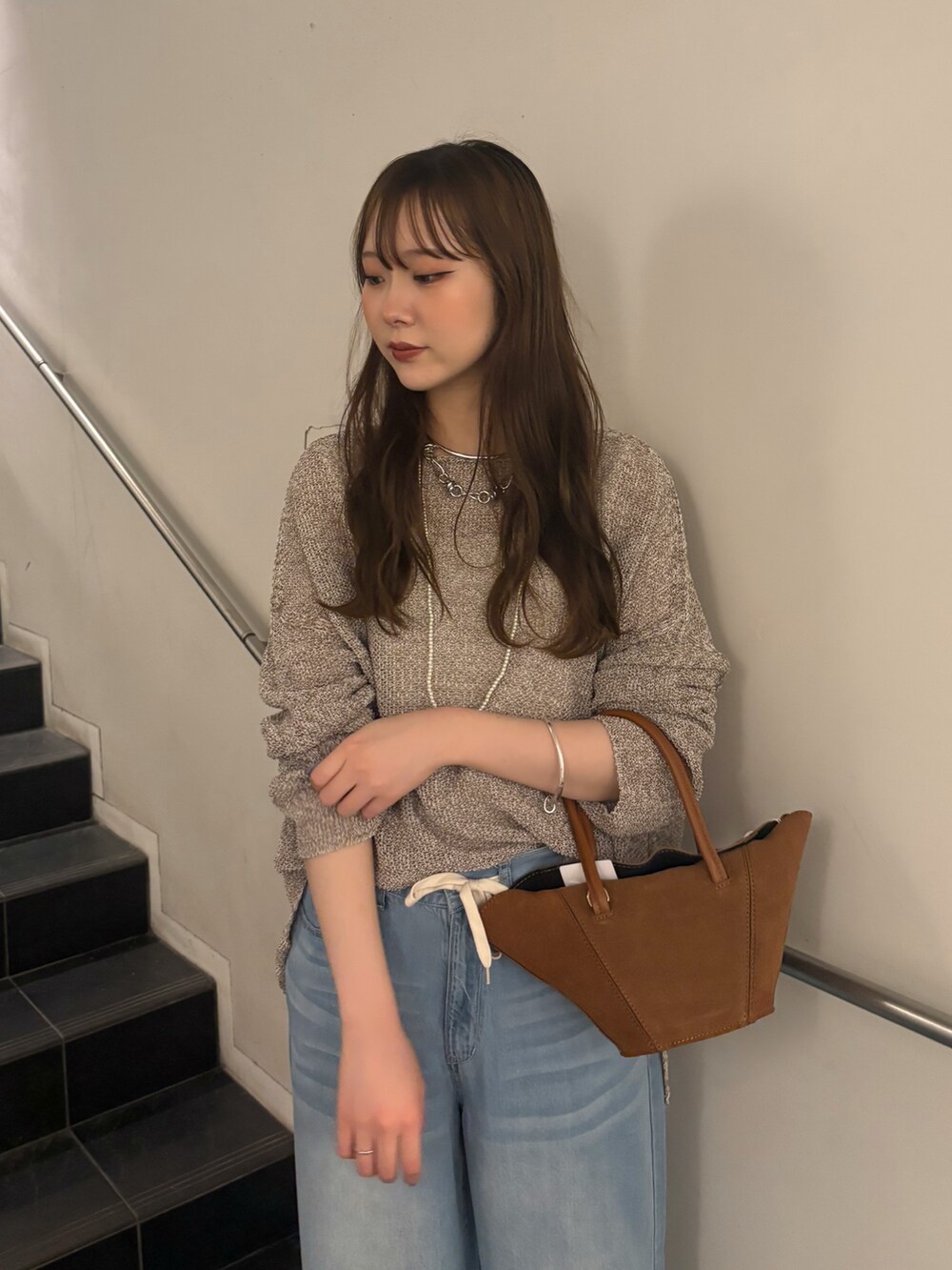 ブルー系のデニムパンツ、ブラック系のサンダル、ベージュ系のニット/セーターを着用したレディースの夏コーディネートの4枚目の写真