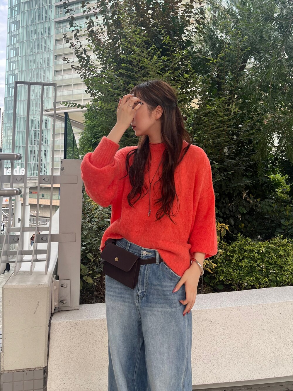 ブルー系のデニムパンツ、ブラウン系のショルダーバッグ、オレンジ系のニット/セーターを着用したレディースの秋コーディネートの3枚目の写真