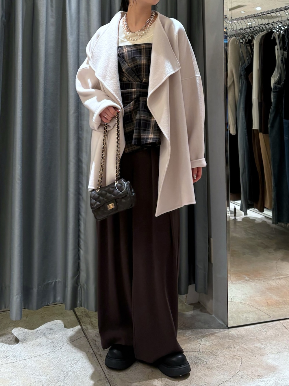 ブラウン系のスラックス、ブラウン系のショルダーバッグ、ブラック系のその他トップスを着用したレディースの冬コーディネートの2枚目の写真