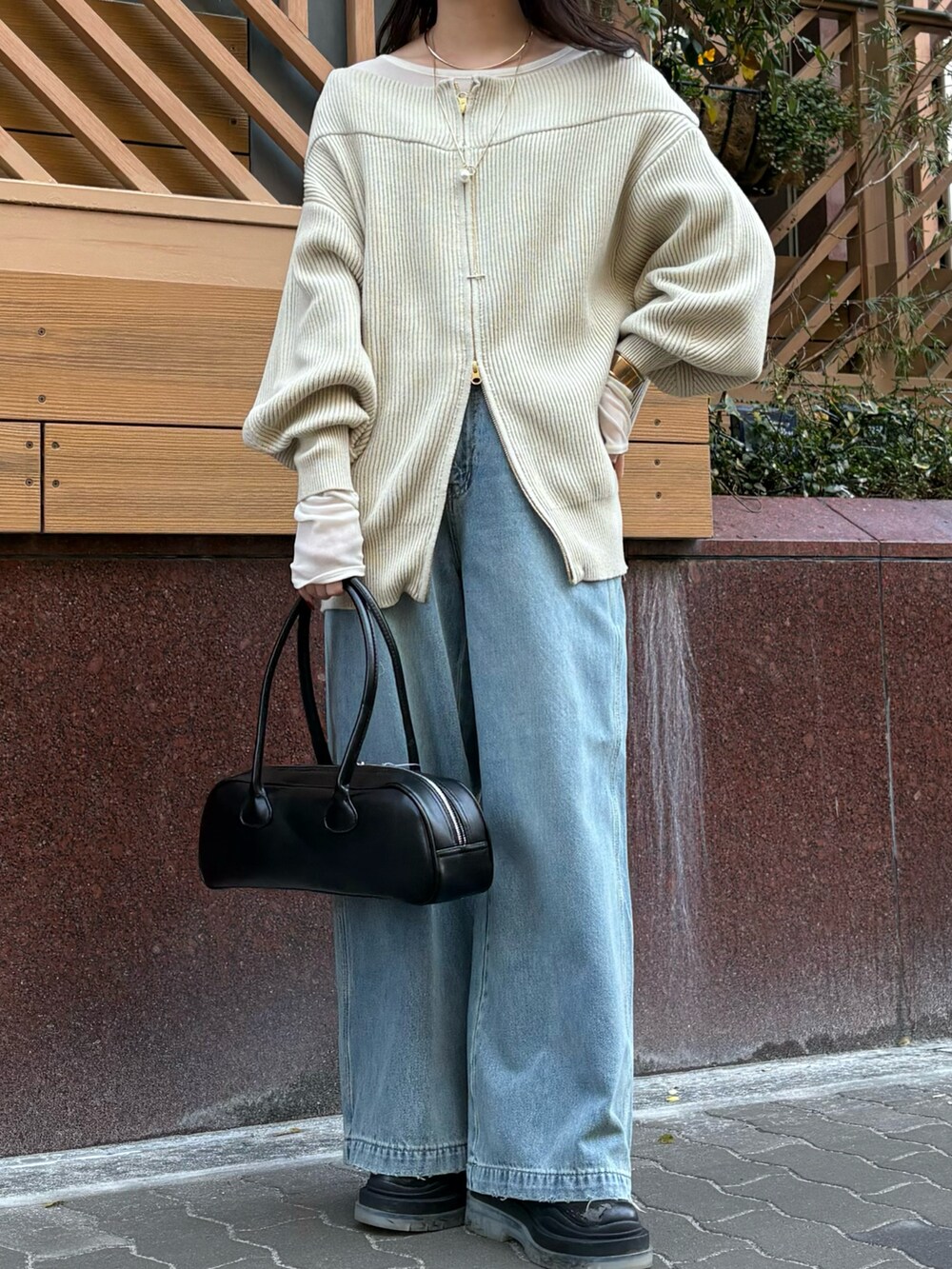 ブルー系のデニムパンツ、ブラック系のショルダーバッグ、ベージュ系のニット/セーターを着用したレディースの冬コーディネートの6枚目の写真