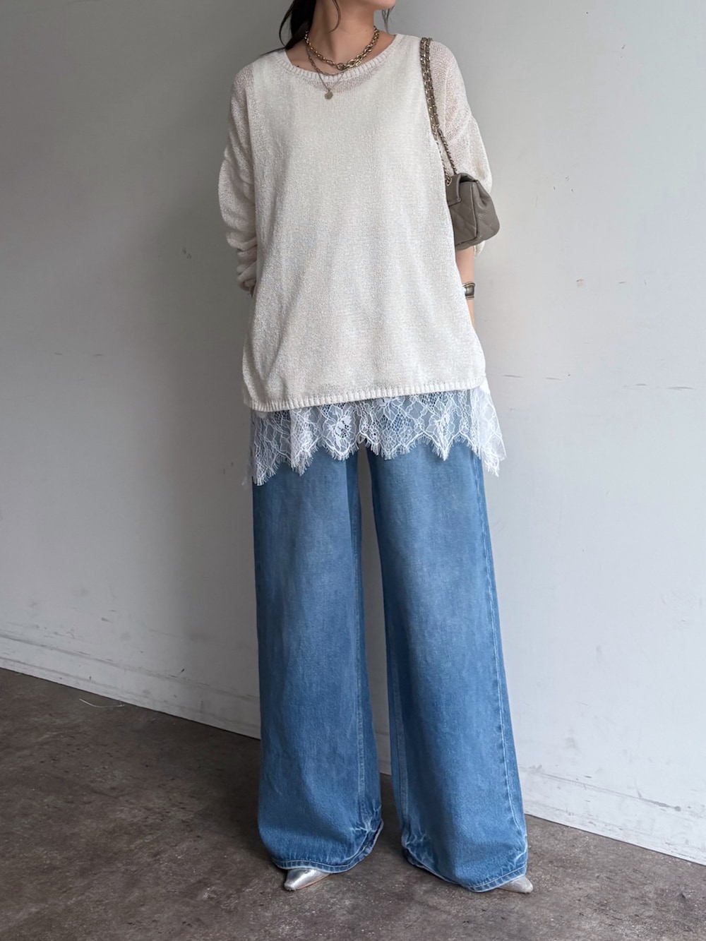 ホワイト系のニット/セーター、ブルー系のデニムパンツ、ホワイト系のTシャツ/カットソーを着用したレディースの春コーディネートの2枚目の写真