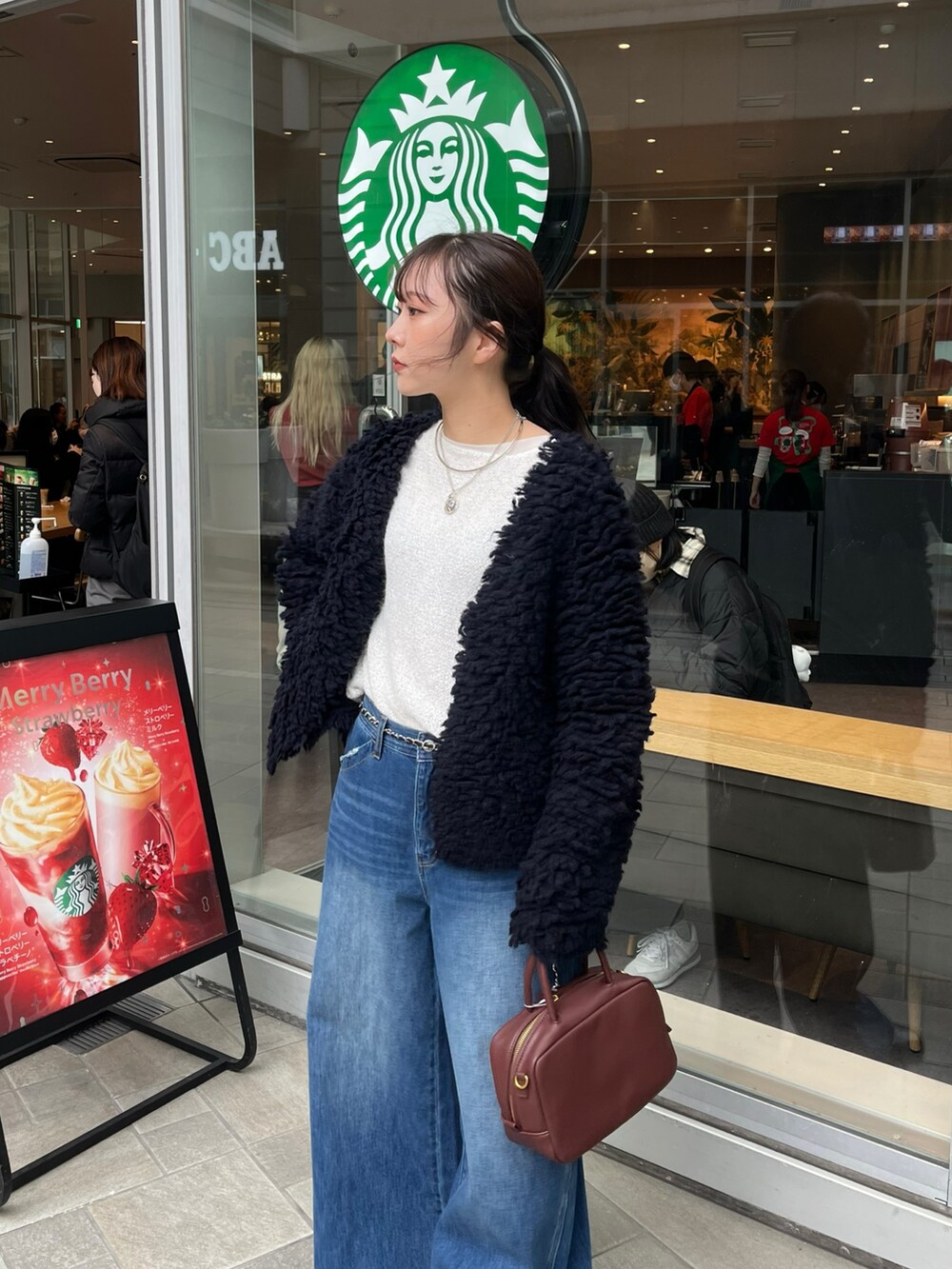 ブルー系のデニムパンツ、ブラウン系のショルダーバッグ、ブルー系のカーディガン/ボレロを着用したレディースの冬コーディネートの3枚目の写真